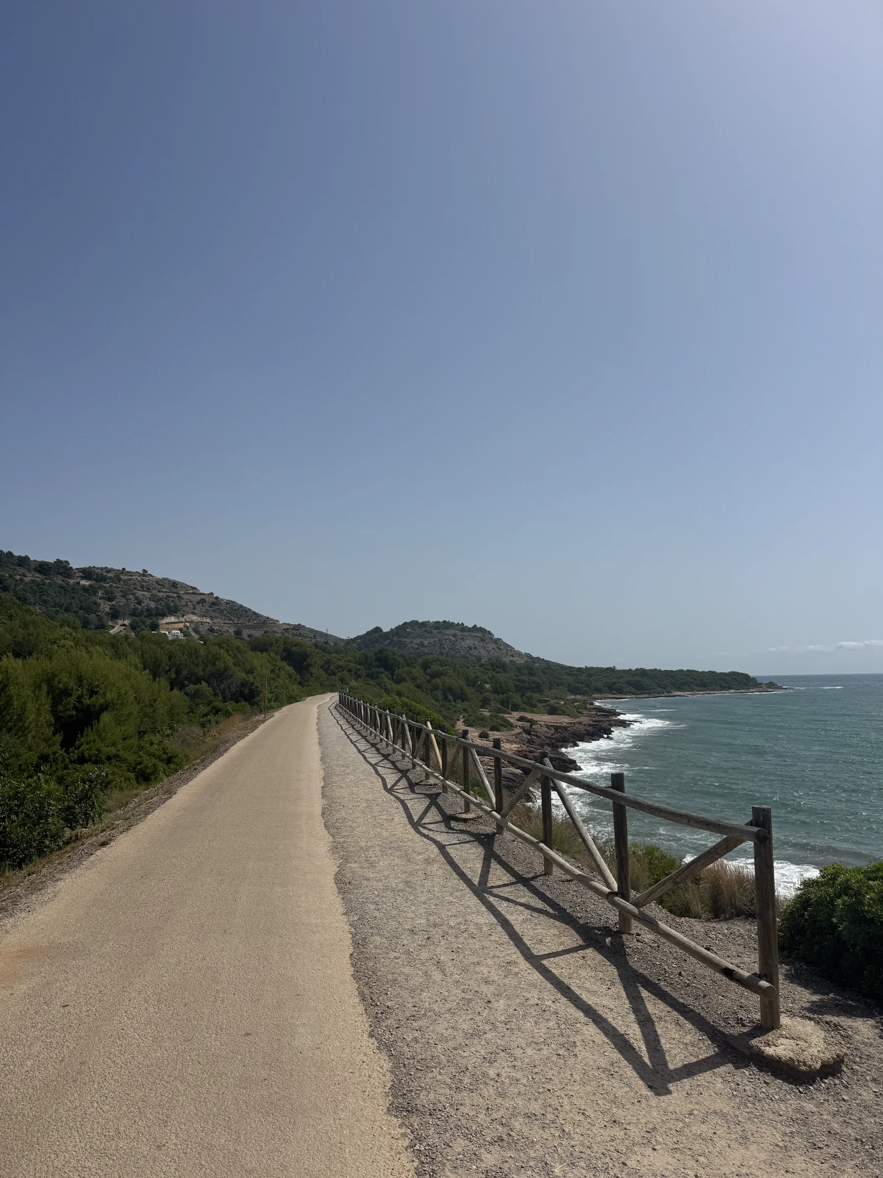An open, empty stretch of Mediterranean coastline under a clear sky.