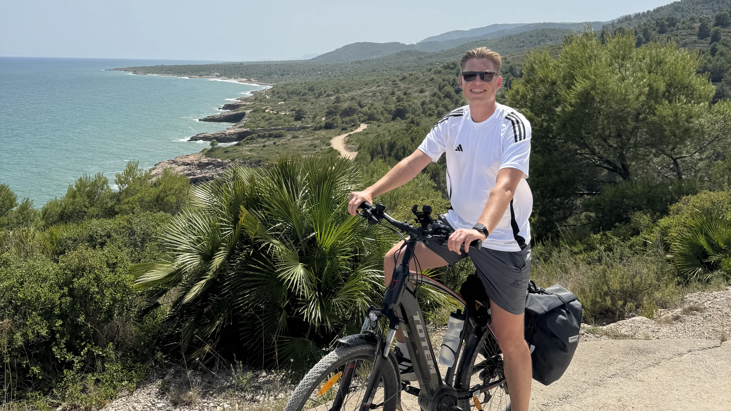 Cyclist with a loaded trekking e-bike overlooking the Mediterranean coast near Valencia.