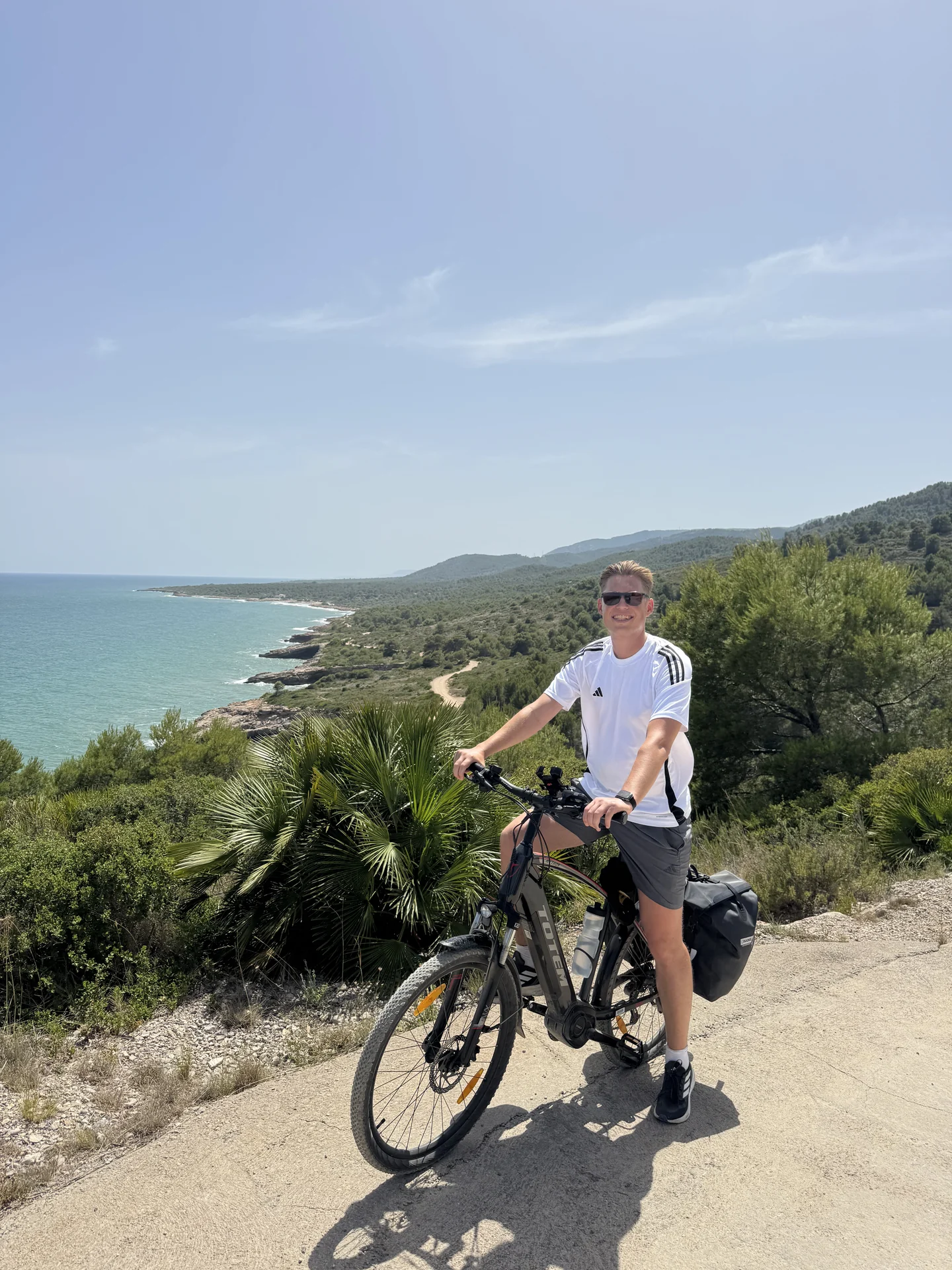 Cyclist with a loaded trekking e-bike overlooking the Mediterranean coast near Valencia.