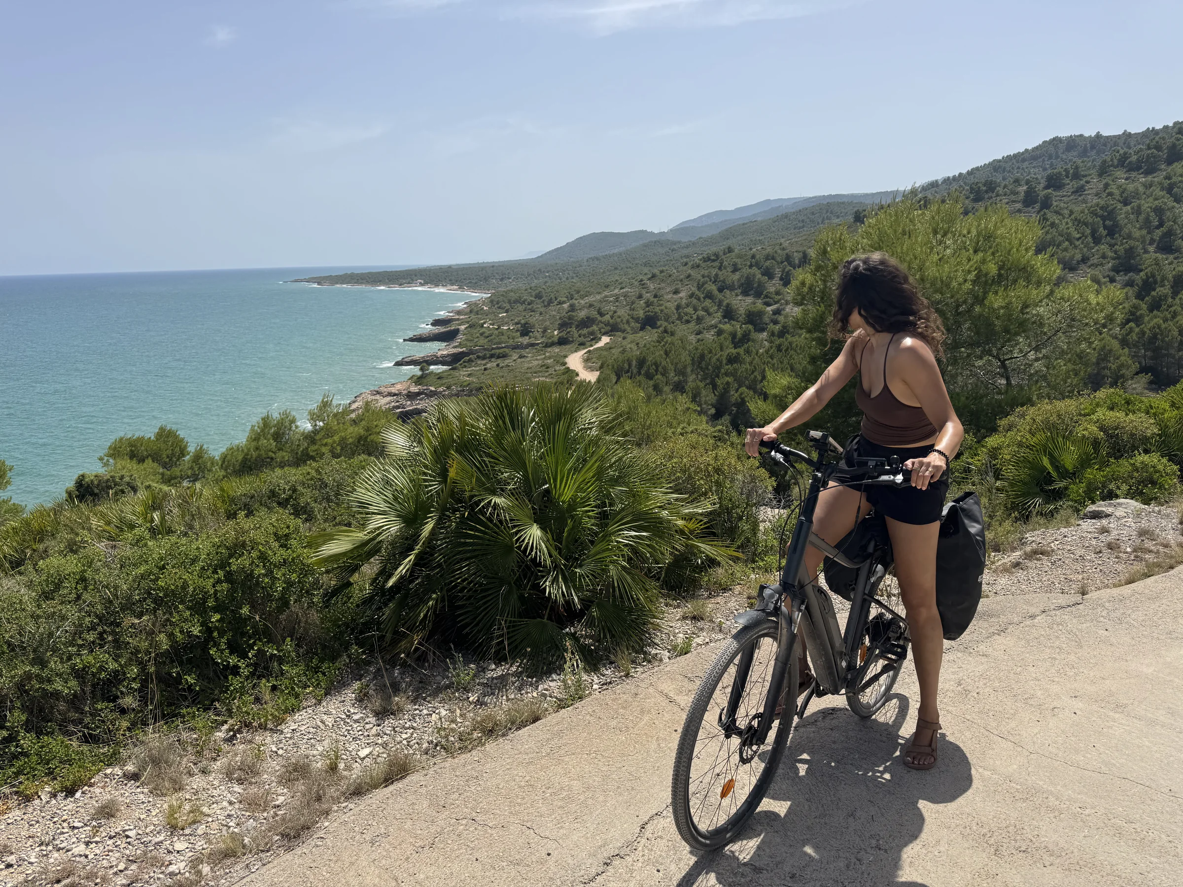 Cyclist riding beside turquoise Mediterranean water on the Costa Azahar coast.