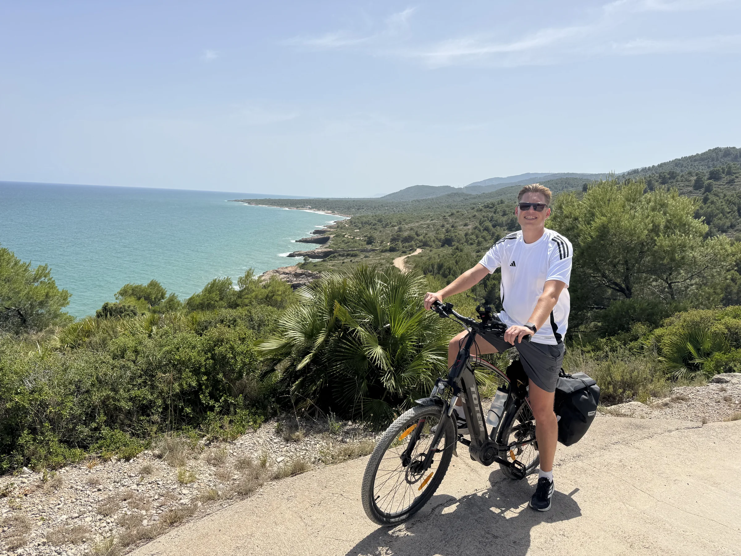 Rider with a loaded e-bike above the green Costa Azahar coastline near Valencia.